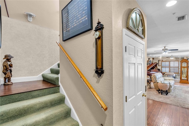 stairs with baseboards, ceiling fan, visible vents, and wood finished floors