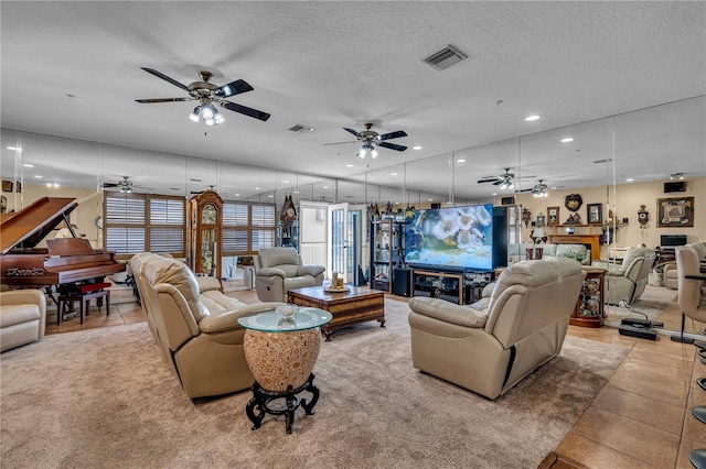 living room featuring light tile patterned floors, a textured ceiling, a fireplace, and visible vents