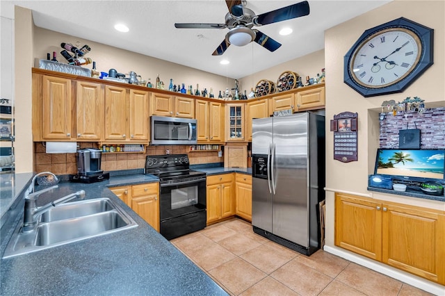 kitchen featuring light tile patterned floors, a sink, appliances with stainless steel finishes, tasteful backsplash, and dark countertops