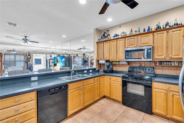 kitchen featuring dark countertops, visible vents, open floor plan, a sink, and black appliances