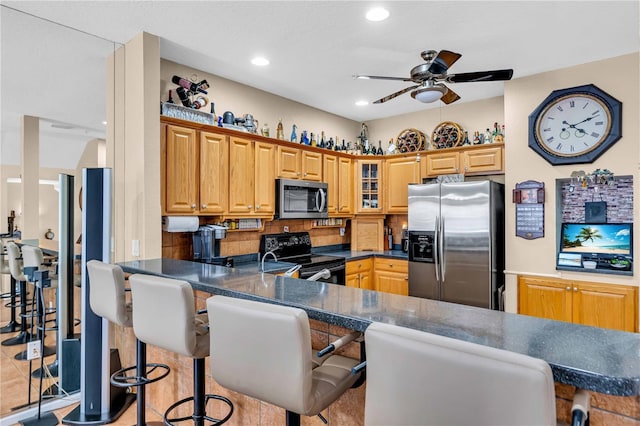 kitchen featuring dark countertops, glass insert cabinets, a kitchen breakfast bar, a peninsula, and stainless steel appliances