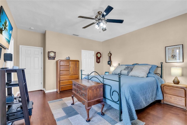 bedroom with dark wood-style floors, visible vents, baseboards, and a ceiling fan