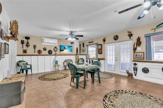 dining space with wainscoting, ceiling fan, a textured ceiling, and a wall mounted air conditioner