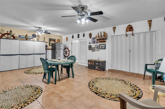 dining room featuring a ceiling fan, light tile patterned flooring, and a textured ceiling