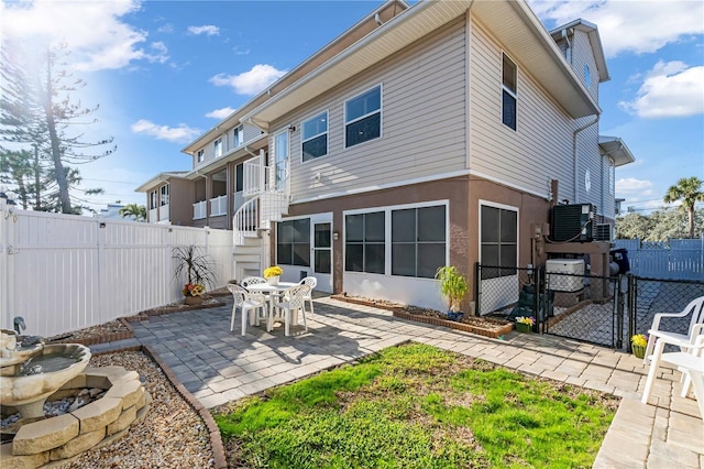 rear view of property with a patio, fence private yard, a gate, and stucco siding