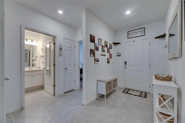 mudroom with light tile patterned floors, baseboards, a sink, and recessed lighting