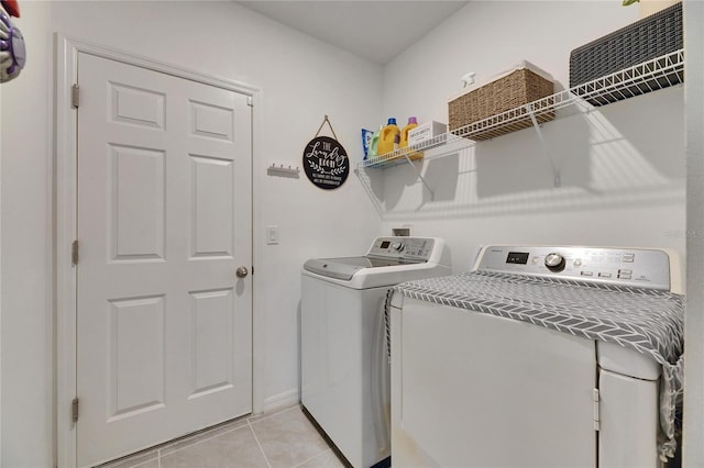 washroom featuring laundry area, light tile patterned flooring, washing machine and clothes dryer, and baseboards