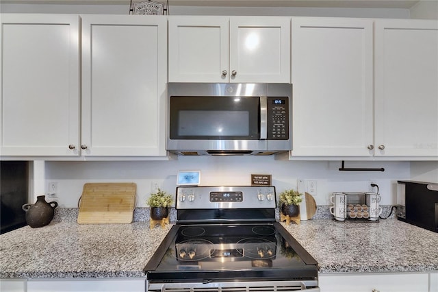 kitchen with appliances with stainless steel finishes, white cabinetry, and light stone countertops