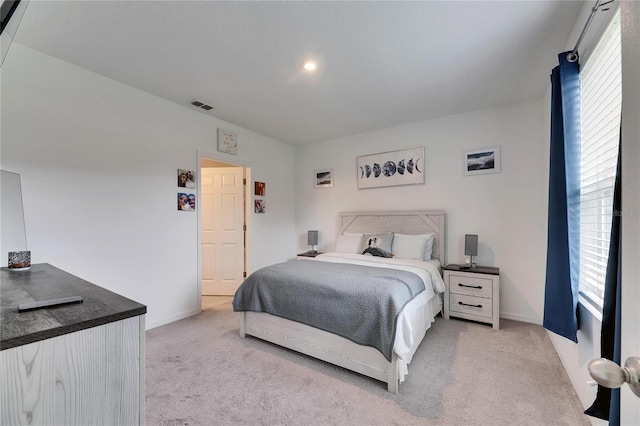 bedroom featuring baseboards, visible vents, and light colored carpet