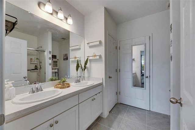 bathroom featuring double vanity, a sink, a shower with shower door, and tile patterned floors