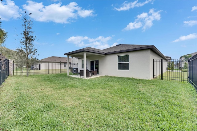 rear view of property featuring a patio area, a fenced backyard, a yard, and stucco siding