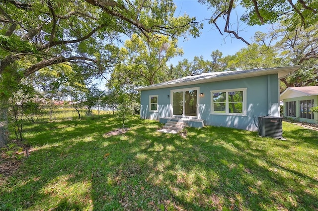 view of front facade featuring a front yard, central AC, and stucco siding