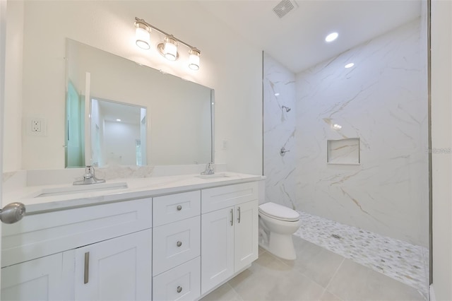 full bathroom featuring a marble finish shower, double vanity, visible vents, toilet, and a sink