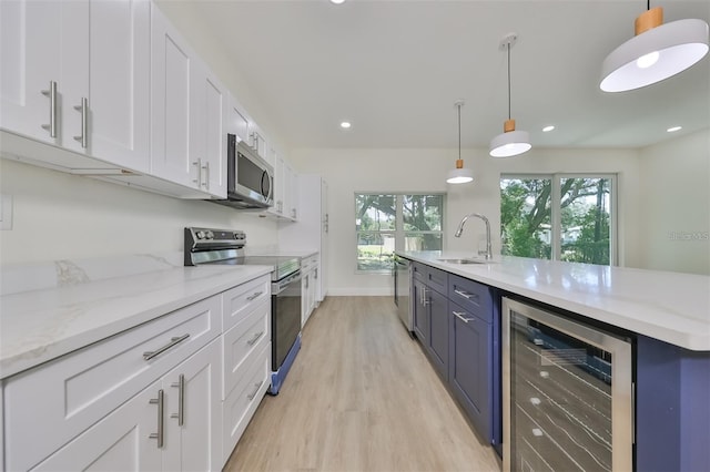 kitchen with stainless steel appliances, wine cooler, white cabinets, and a sink