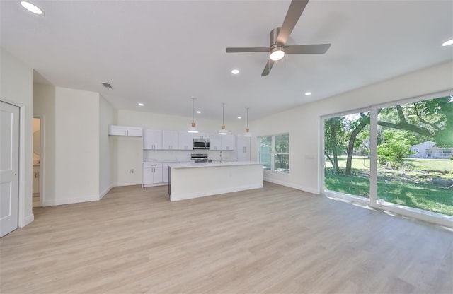 kitchen featuring a kitchen island, white cabinetry, light countertops, hanging light fixtures, and appliances with stainless steel finishes