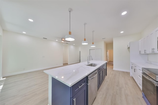 kitchen with a sink, white cabinets, appliances with stainless steel finishes, an island with sink, and decorative light fixtures