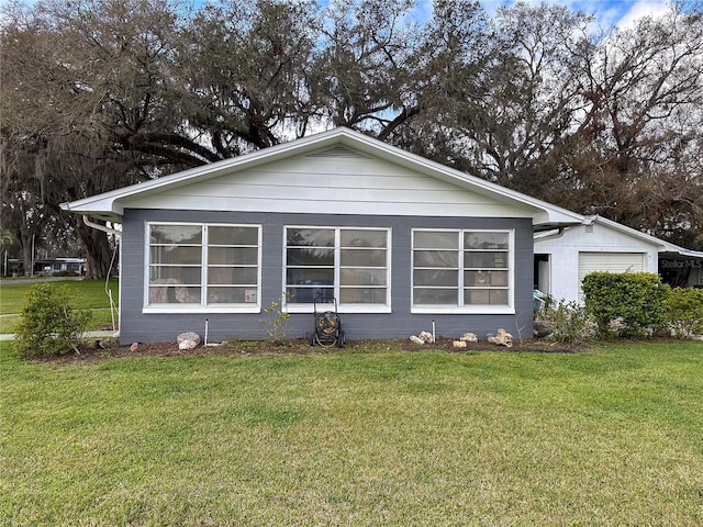 rear view of property featuring a garage and a yard