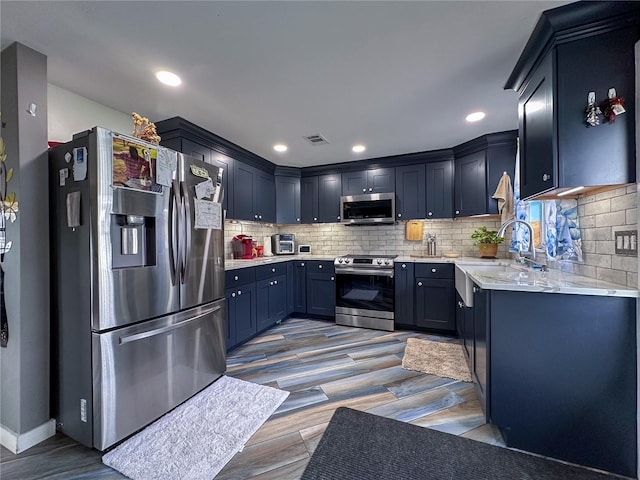 kitchen with stainless steel appliances, tasteful backsplash, recessed lighting, and blue cabinets