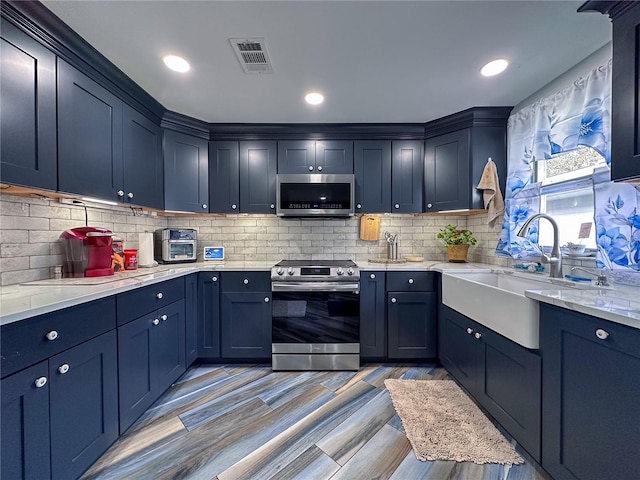 kitchen featuring blue cabinetry, visible vents, appliances with stainless steel finishes, and a sink