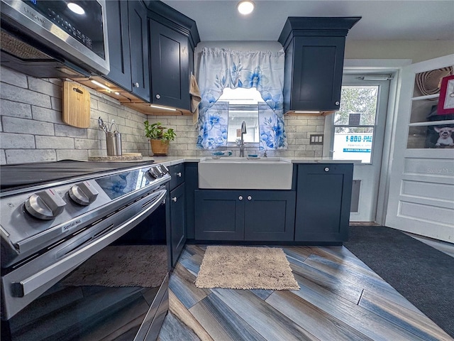 kitchen featuring light countertops, appliances with stainless steel finishes, a sink, and blue cabinets