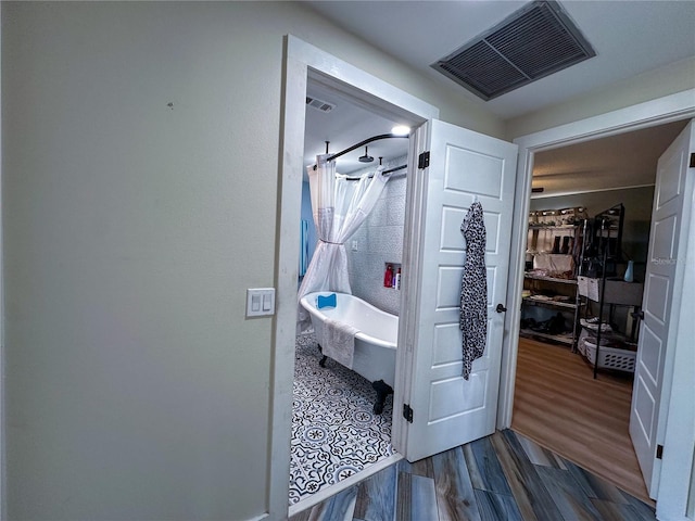 bathroom featuring a soaking tub, wood finished floors, and visible vents