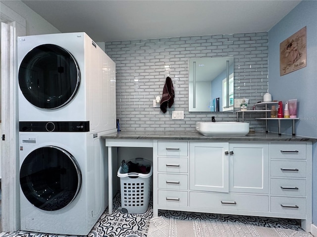 clothes washing area with laundry area, light tile patterned flooring, a sink, and stacked washer and clothes dryer