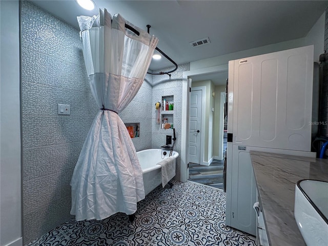 bathroom with stacked washer / dryer, visible vents, and tile patterned floors