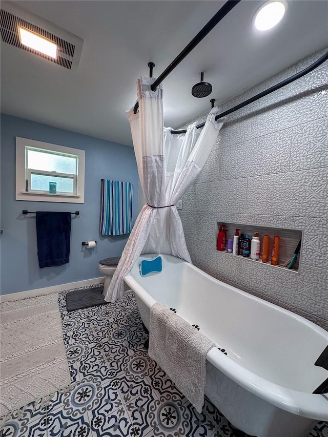 bathroom featuring toilet, baseboards, visible vents, and shower / tub combo with curtain