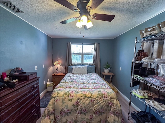 bedroom with baseboards, ceiling fan, visible vents, and a textured ceiling