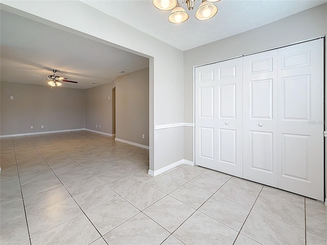 interior space with a closet, baseboards, a notable chandelier, and light tile patterned flooring