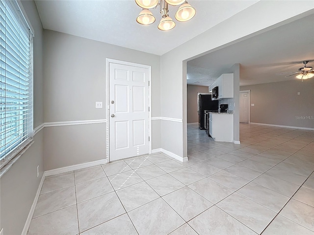 foyer with light tile patterned floors, ceiling fan with notable chandelier, and baseboards