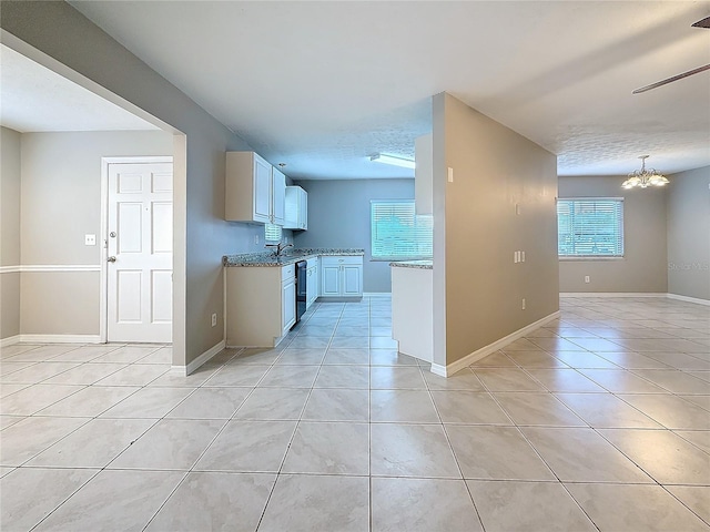 kitchen with light tile patterned floors, baseboards, open floor plan, an inviting chandelier, and white cabinetry