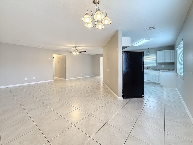 unfurnished room featuring light tile patterned floors, visible vents, a sink, and ceiling fan with notable chandelier