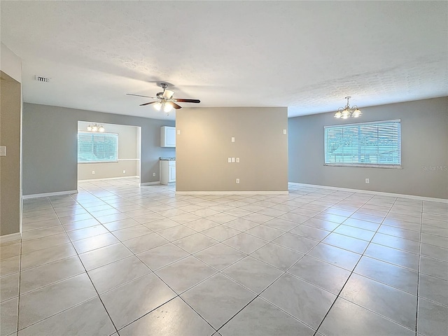 spare room featuring light tile patterned floors, baseboards, visible vents, a textured ceiling, and ceiling fan with notable chandelier