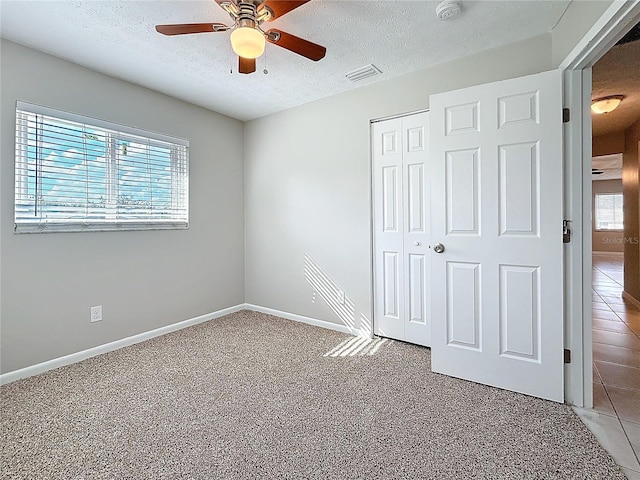 unfurnished bedroom featuring carpet, a closet, visible vents, a textured ceiling, and baseboards