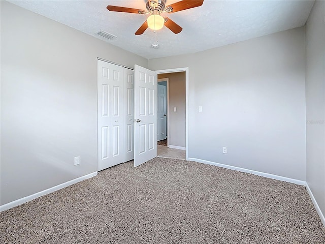 unfurnished bedroom with a textured ceiling, baseboards, visible vents, and light colored carpet