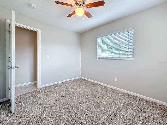 carpeted spare room with ceiling fan, baseboards, and a textured ceiling