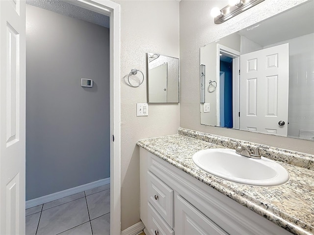 bathroom with tile patterned flooring, vanity, and baseboards