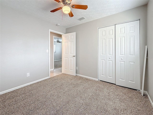 unfurnished bedroom with a textured ceiling, light colored carpet, visible vents, baseboards, and a closet