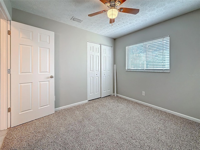 unfurnished bedroom featuring a textured ceiling, visible vents, baseboards, a closet, and carpet