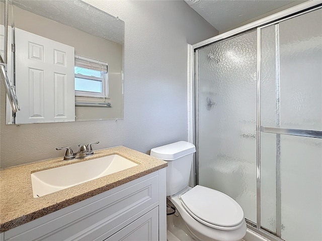 bathroom with a stall shower, a textured wall, toilet, a textured ceiling, and vanity