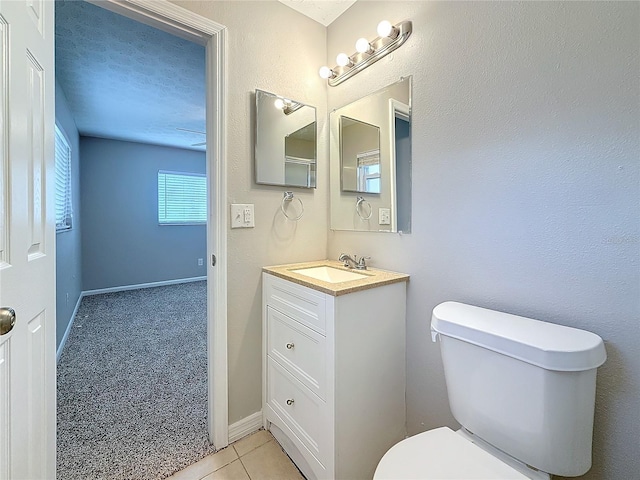 half bath with toilet, vanity, a textured ceiling, tile patterned flooring, and baseboards