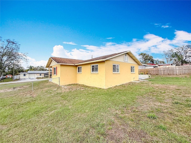 view of side of property with a yard, fence, and stucco siding