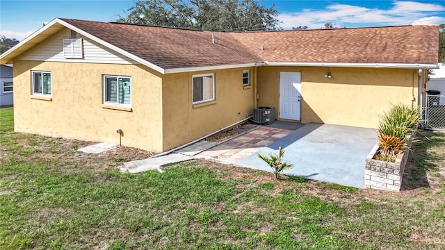 rear view of property with a patio area, a shingled roof, a lawn, and stucco siding