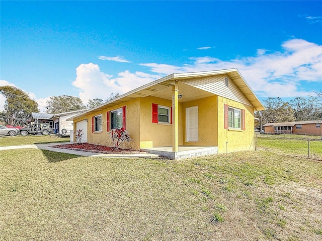 view of side of property with a garage, a lawn, fence, and stucco siding