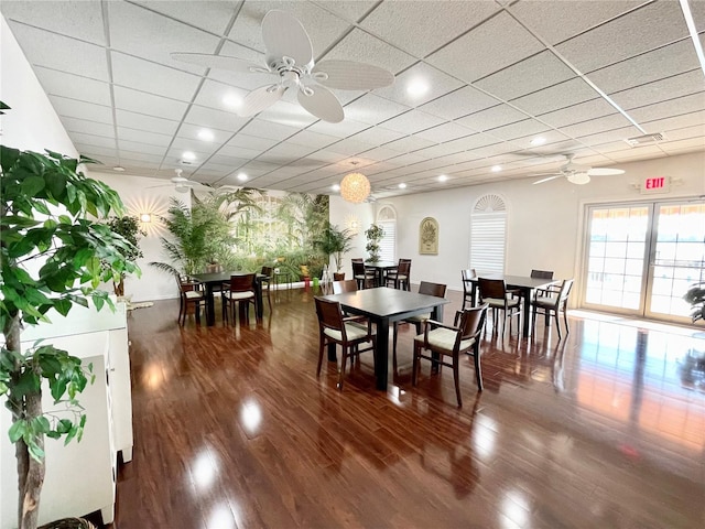 dining room featuring a ceiling fan, a drop ceiling, and wood finished floors