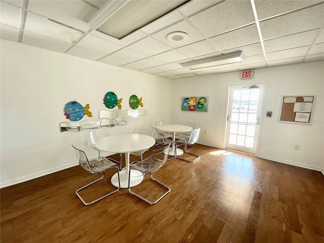 dining space featuring a paneled ceiling, baseboards, and wood finished floors