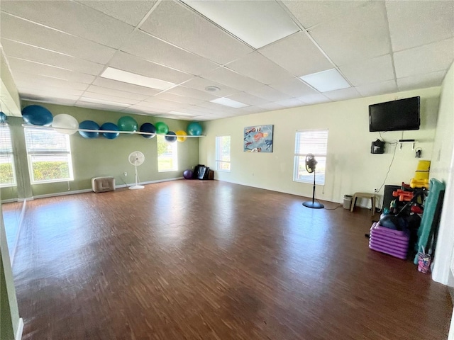 workout room with a paneled ceiling, baseboards, and wood finished floors