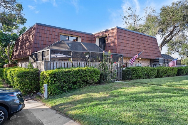 view of home's exterior with brick siding, a tiled roof, mansard roof, and a yard