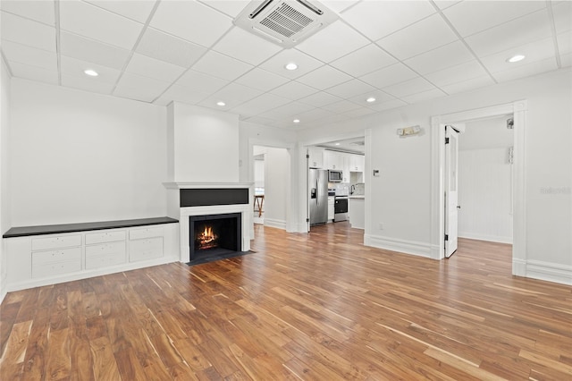 unfurnished living room featuring a fireplace with flush hearth, visible vents, baseboards, and wood finished floors